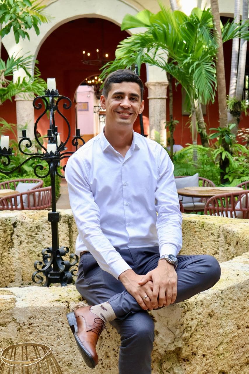 Jhonna Galeano sentado en un patio rodeado de plantas